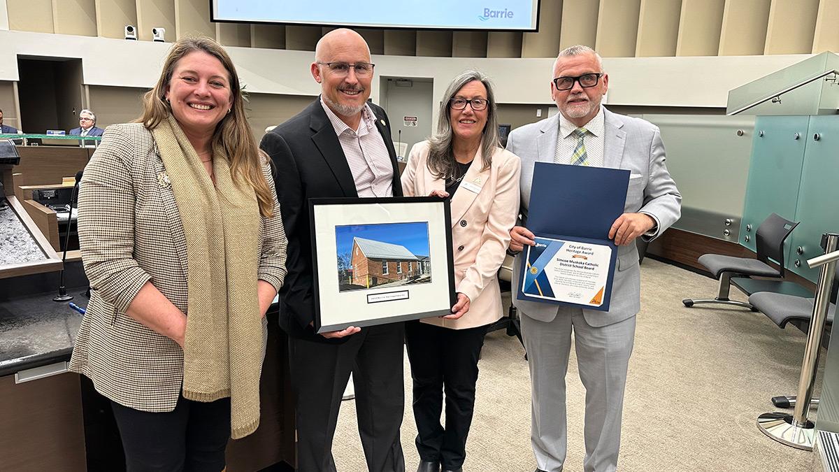 Councillor Kungl, Craig Elliot, Janice Hutchison and Deputy Mayor Thomson pose with a framed photo of the schoolhouse and the award