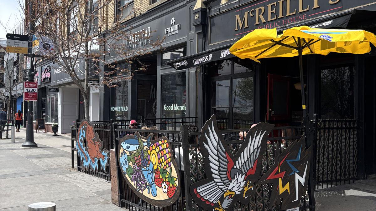 McReilly's with colourful artwork on the patio fence, including a water spirit with the body of a lynx and a serpent tail, a plate of food and a Thunderbird.