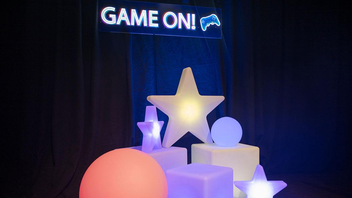 Colourful, illuminated geometric shapes with a "GAME ON!" sign against a dark background.