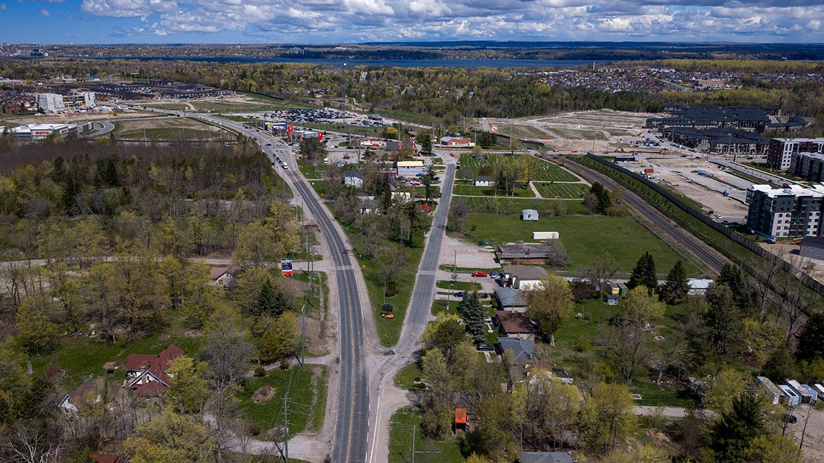 Aerial view of two roads surrounded by green trees and scattered houses.