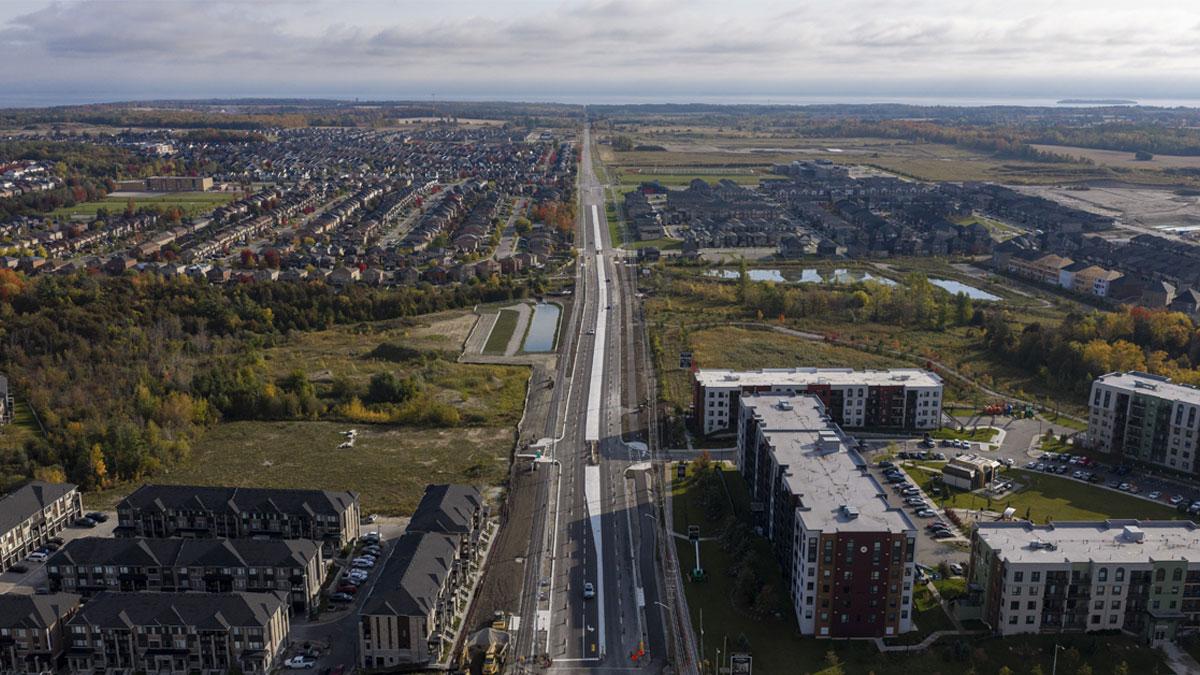 Aerial view of a suburban landscape with roads, residential buildings, and green fields.