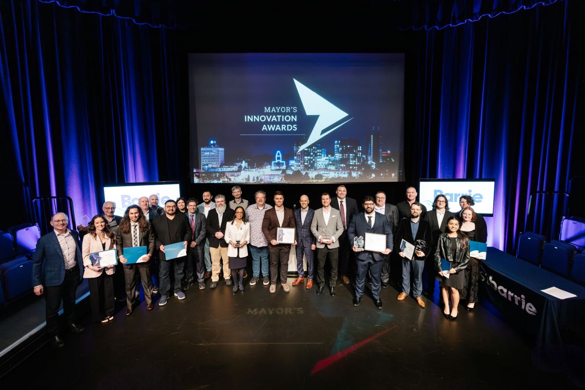 Group of award recipients on stage, with a large screen displaying the event logo behind them.