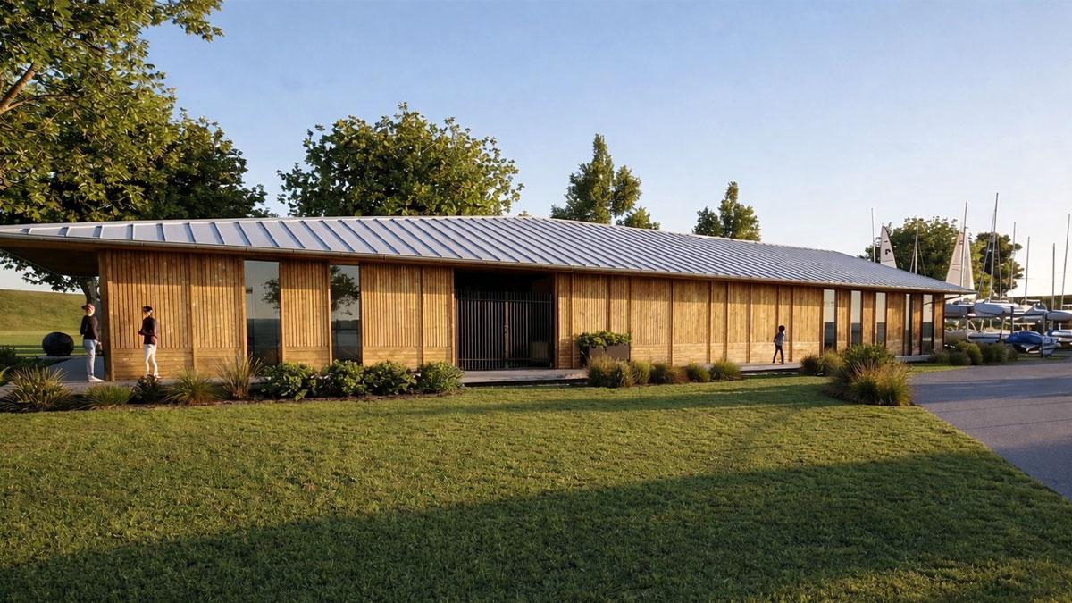 Modern wooden building with a sloped roof, surrounded by grass and trees.