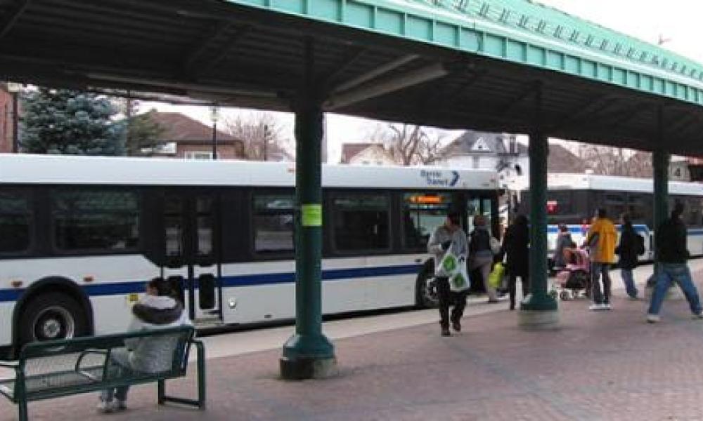 People at transit terminal with bus in background